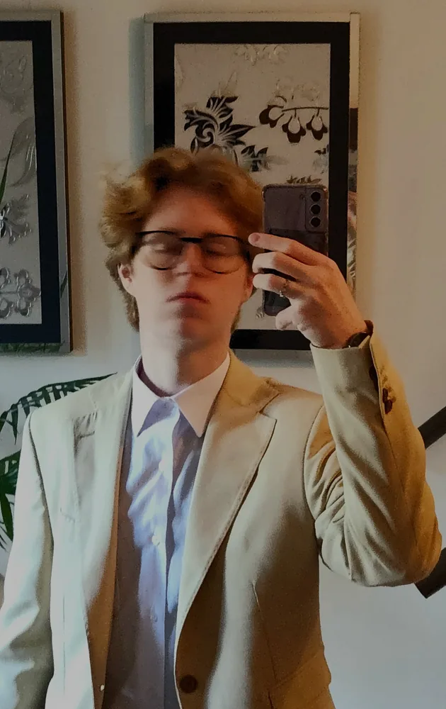Mirror self-portrait of Carlos Leonardo wearing a light suit