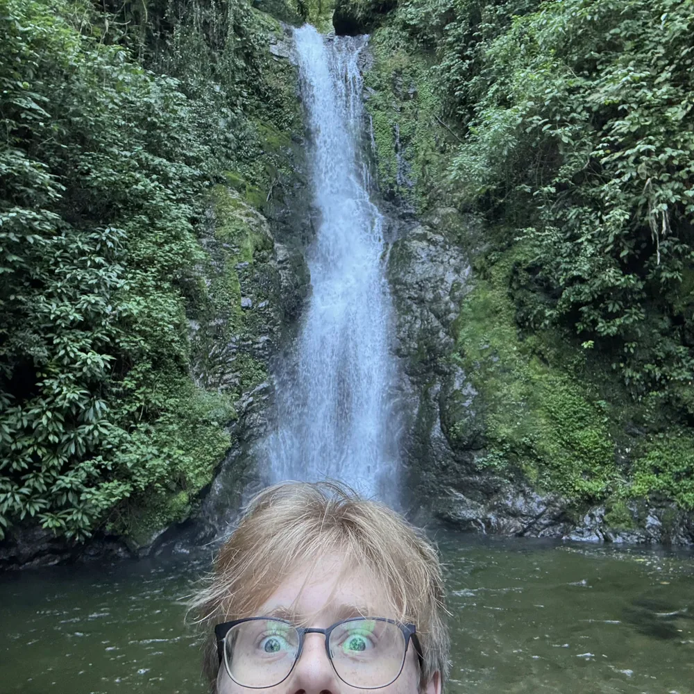 Carlos Leonardo in front of a waterfall surrounded by forest